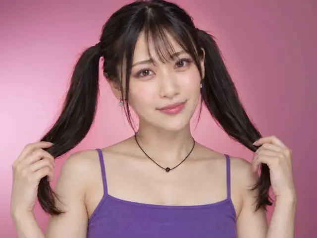 ピンクの背景でツインテールを持ってカメラを見る女性