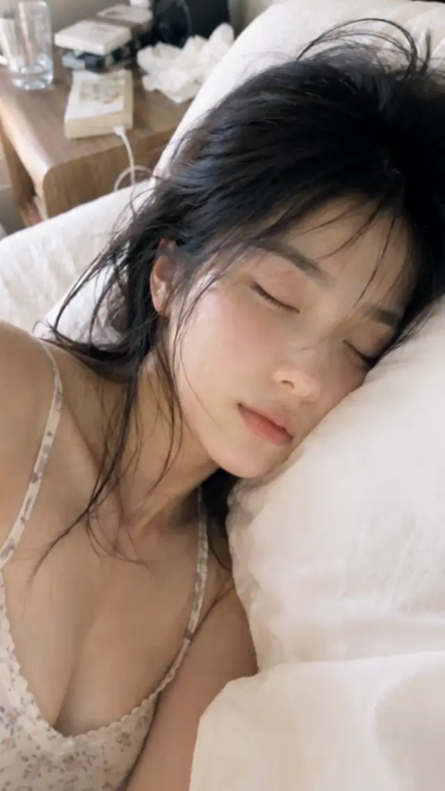 朝の光が差す白い枕で眠る黒髪の女性